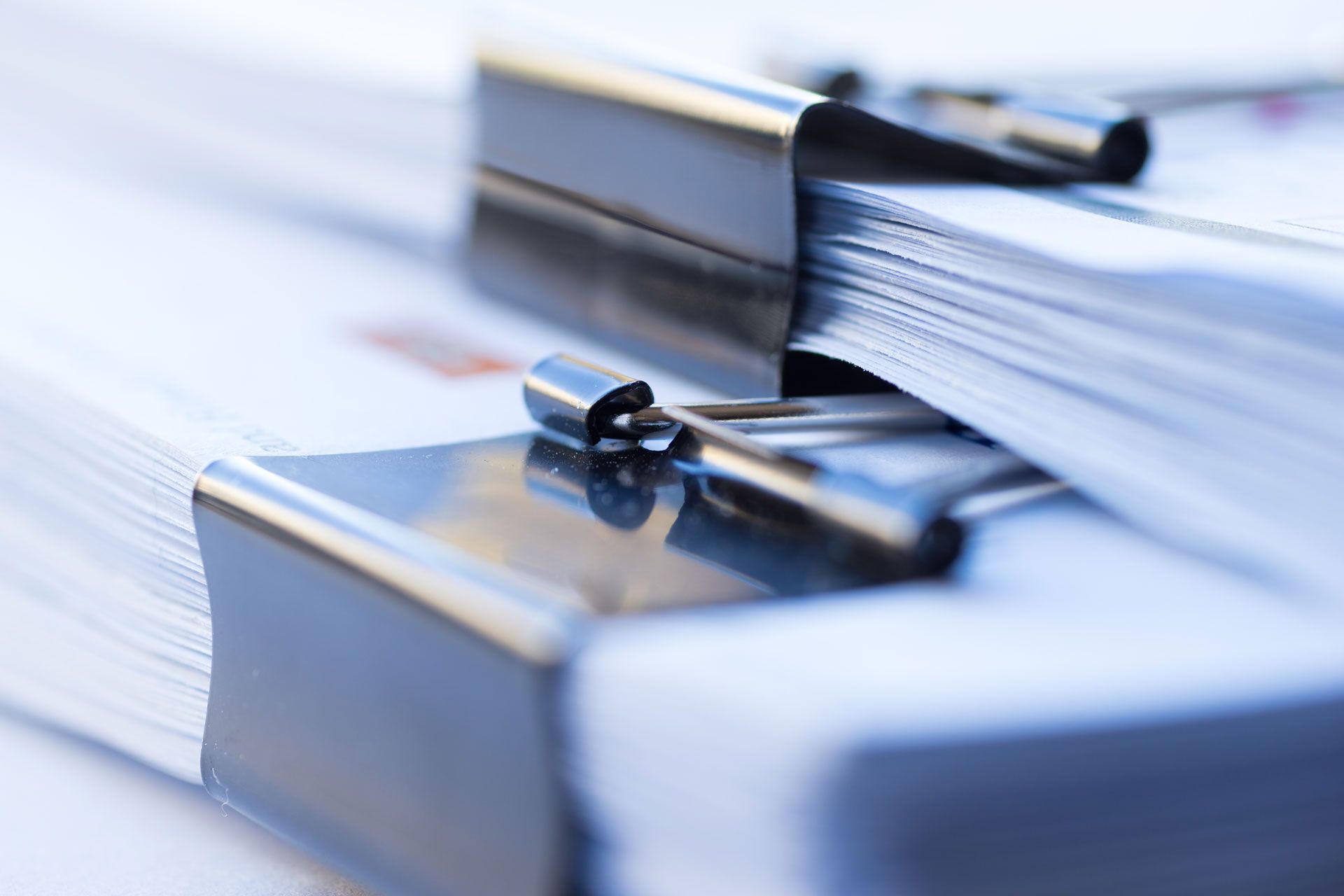Two stacks of white paper clipped together with black metal binder clips.