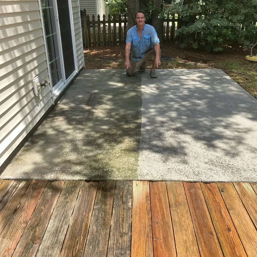 A man is cleaning a patio with a high pressure washer.