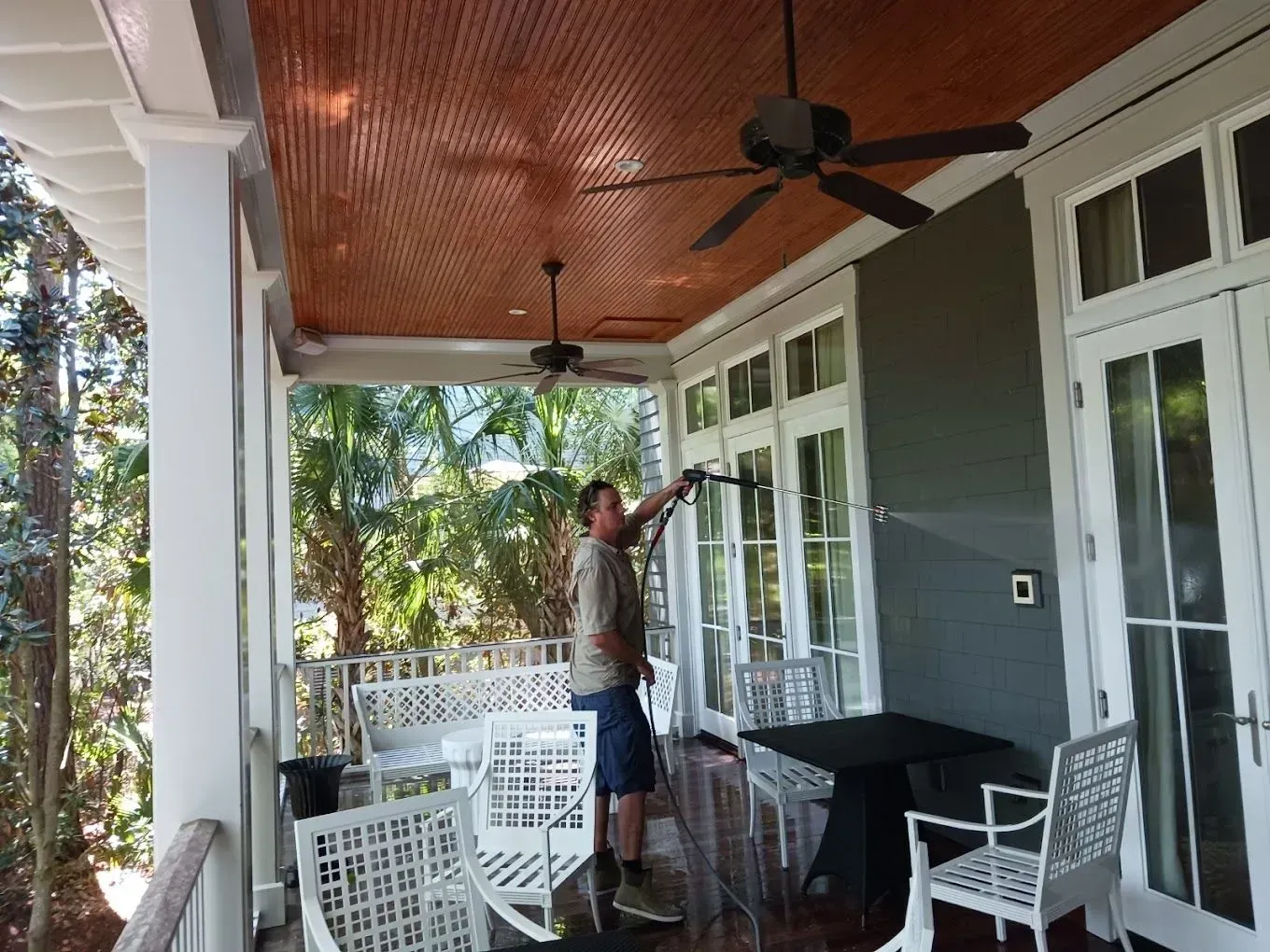 A person is cleaning a siding with a brush and a hose.