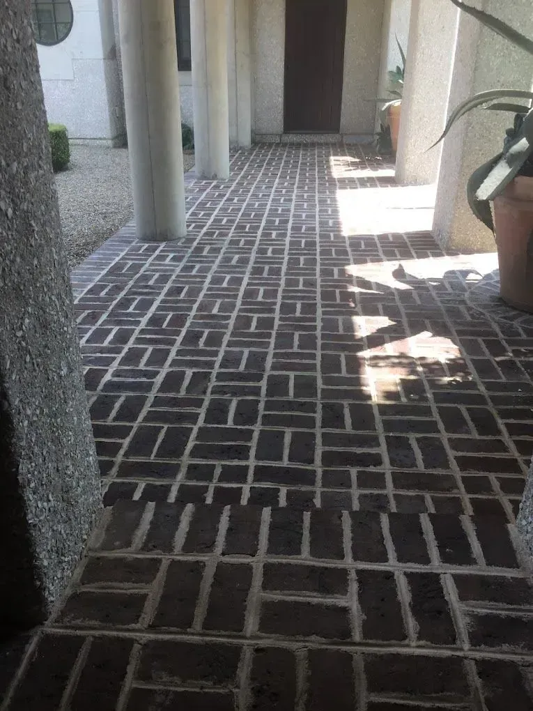 A brick walkway with columns and potted plants
