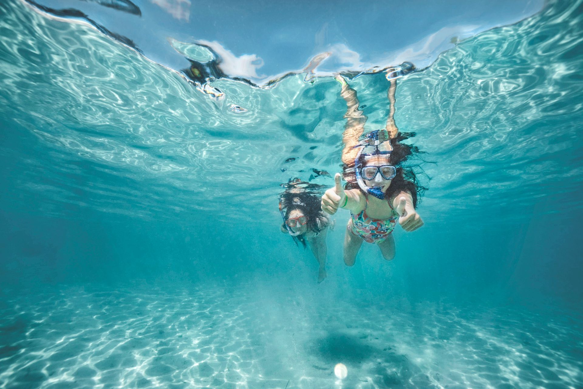 Two snorkelers floating in clear turquoise water near the surface