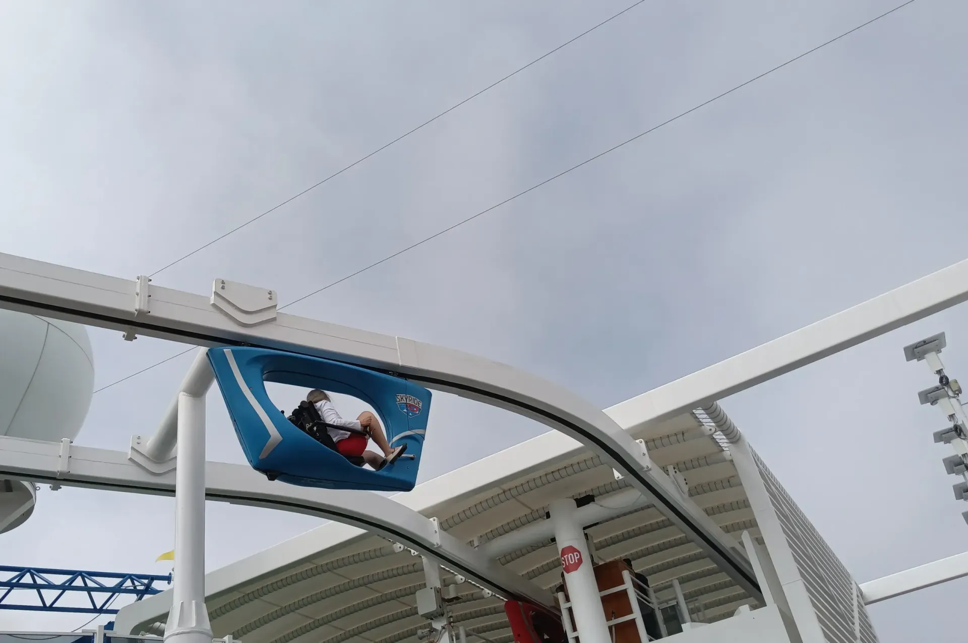 A person in a blue banner hangs from a stadium roof under an overcast sky.