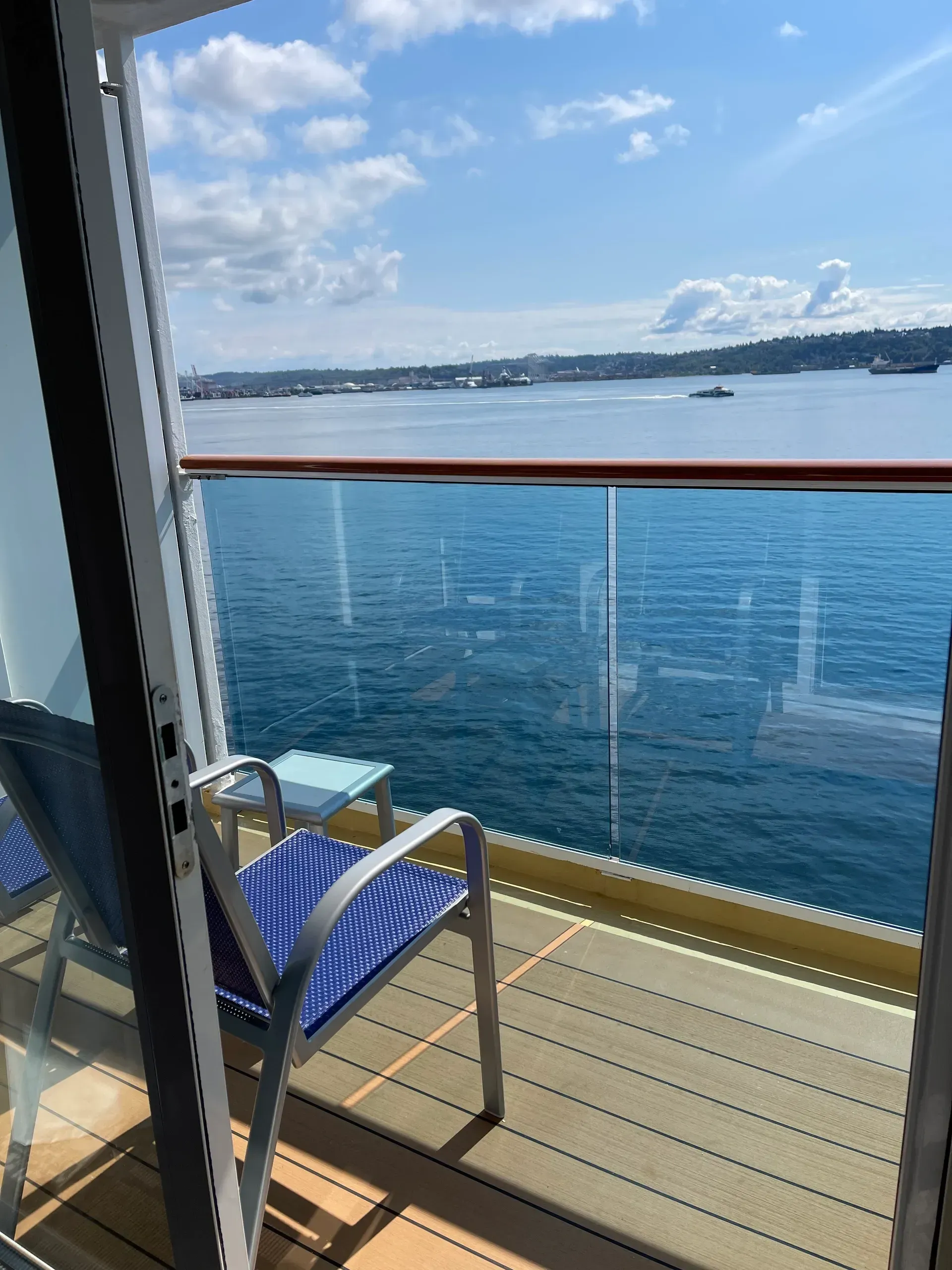 Balcony lounge chair overlooking a blue harbor under a partly cloudy sky