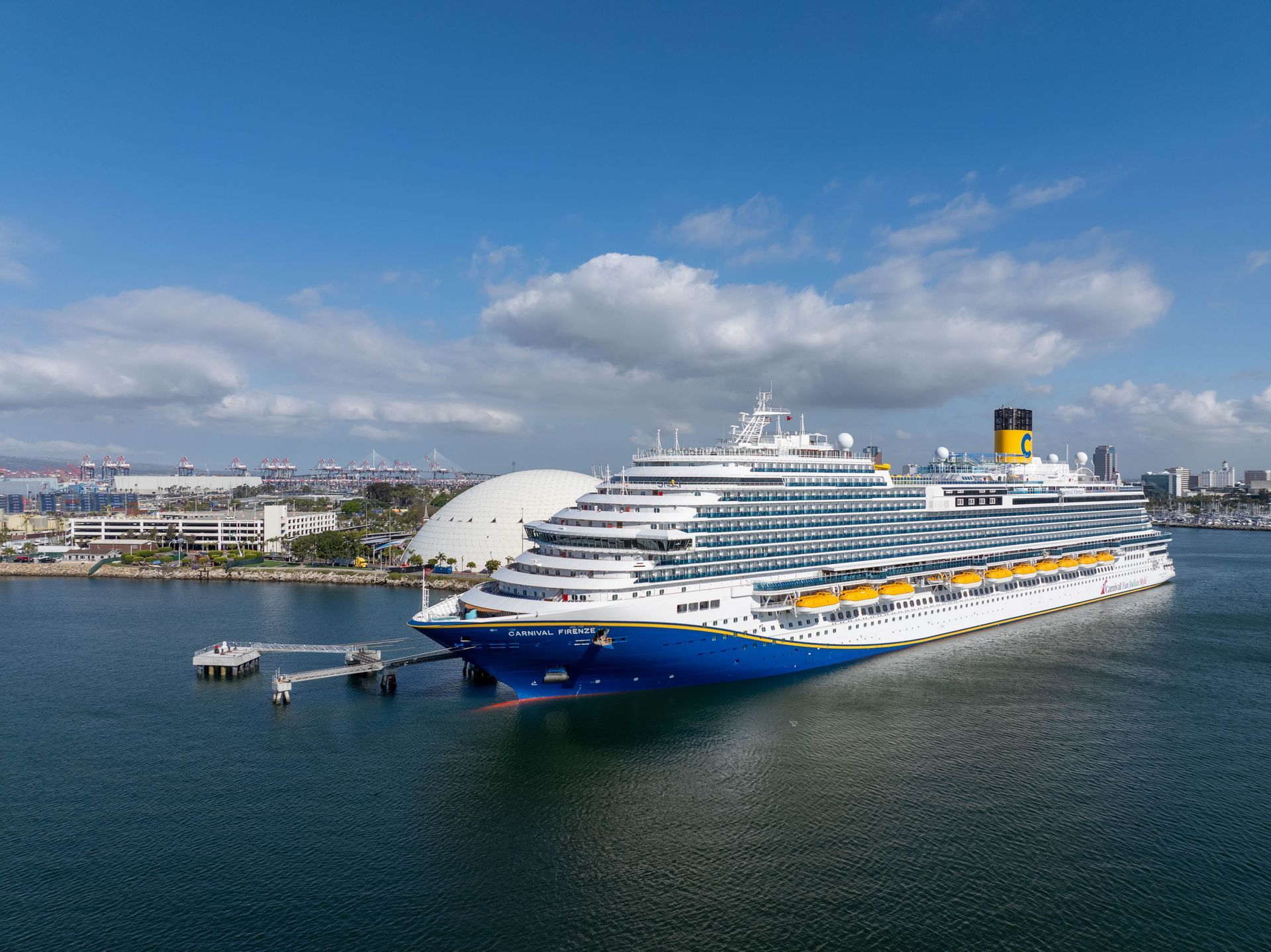 Large white cruise ship docked in a harbor under a blue sky