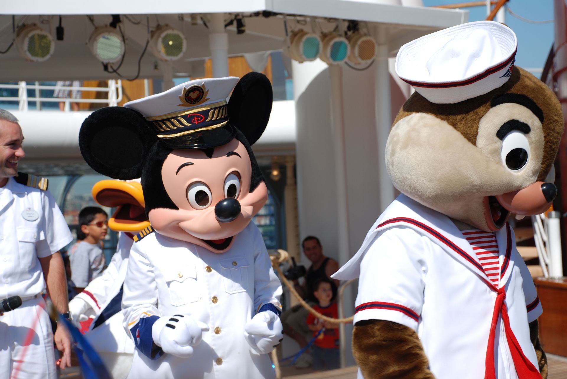 Mickey Mouse and Chip in white sailor outfits walking at a Disney parade