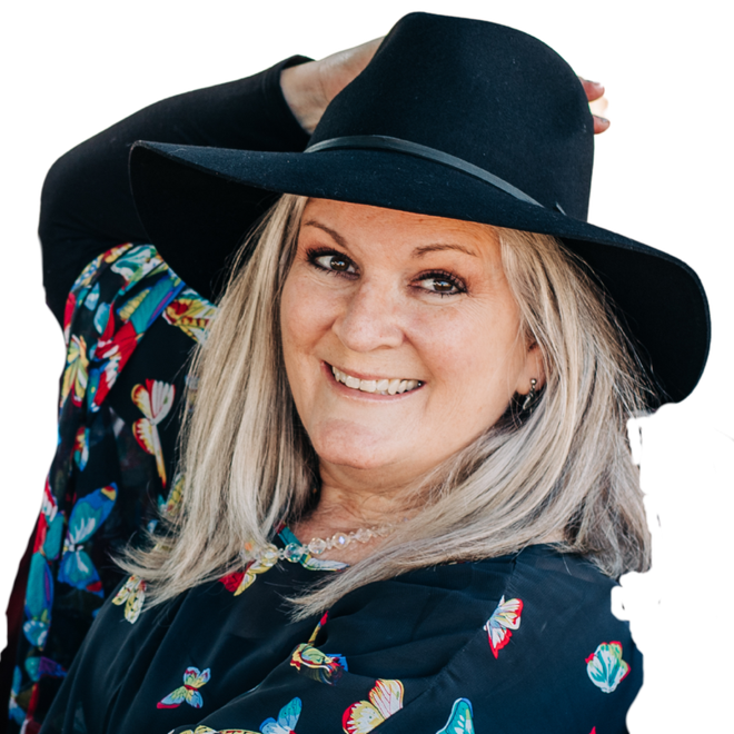 Smiling person in a black hat and floral shirt against a white background