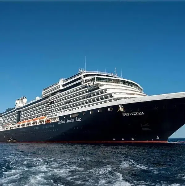 Large black-and-white cruise ship on blue water under a clear sky