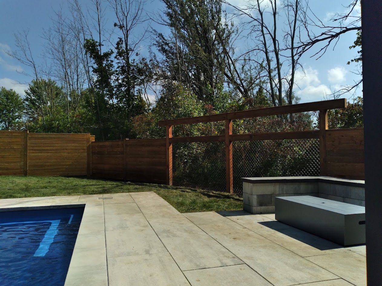 A wooden fence beside a brick pathway with a garden.