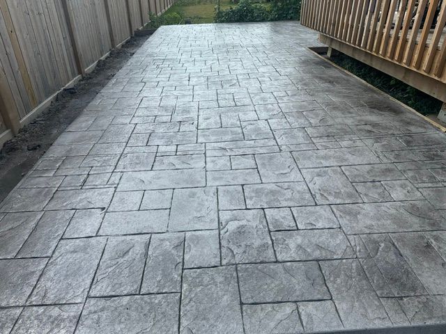 Wooden deck with black railings and steps leading down to a brick patio.