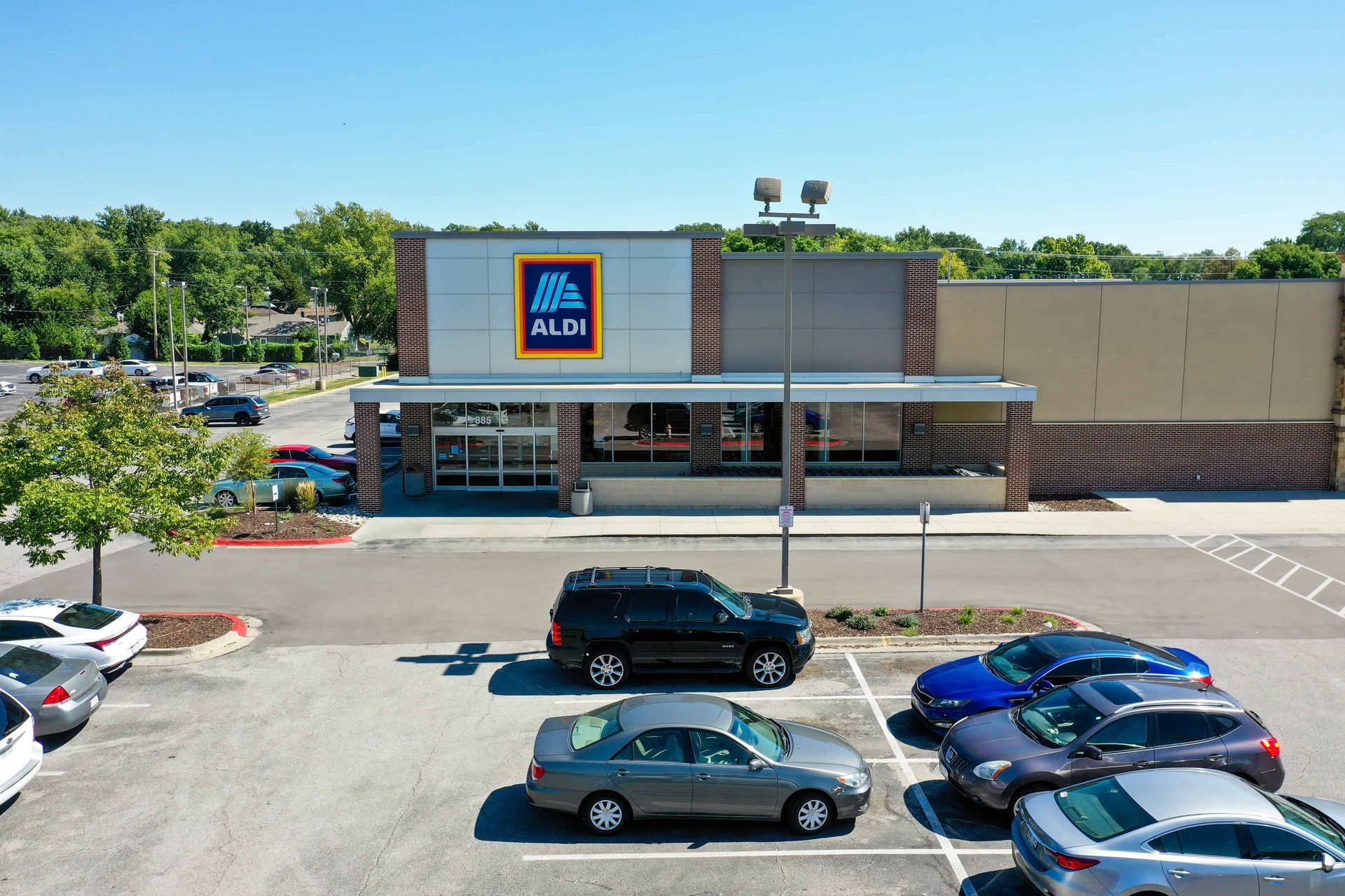 Aldi storefront with parked cars in front on a sunny day