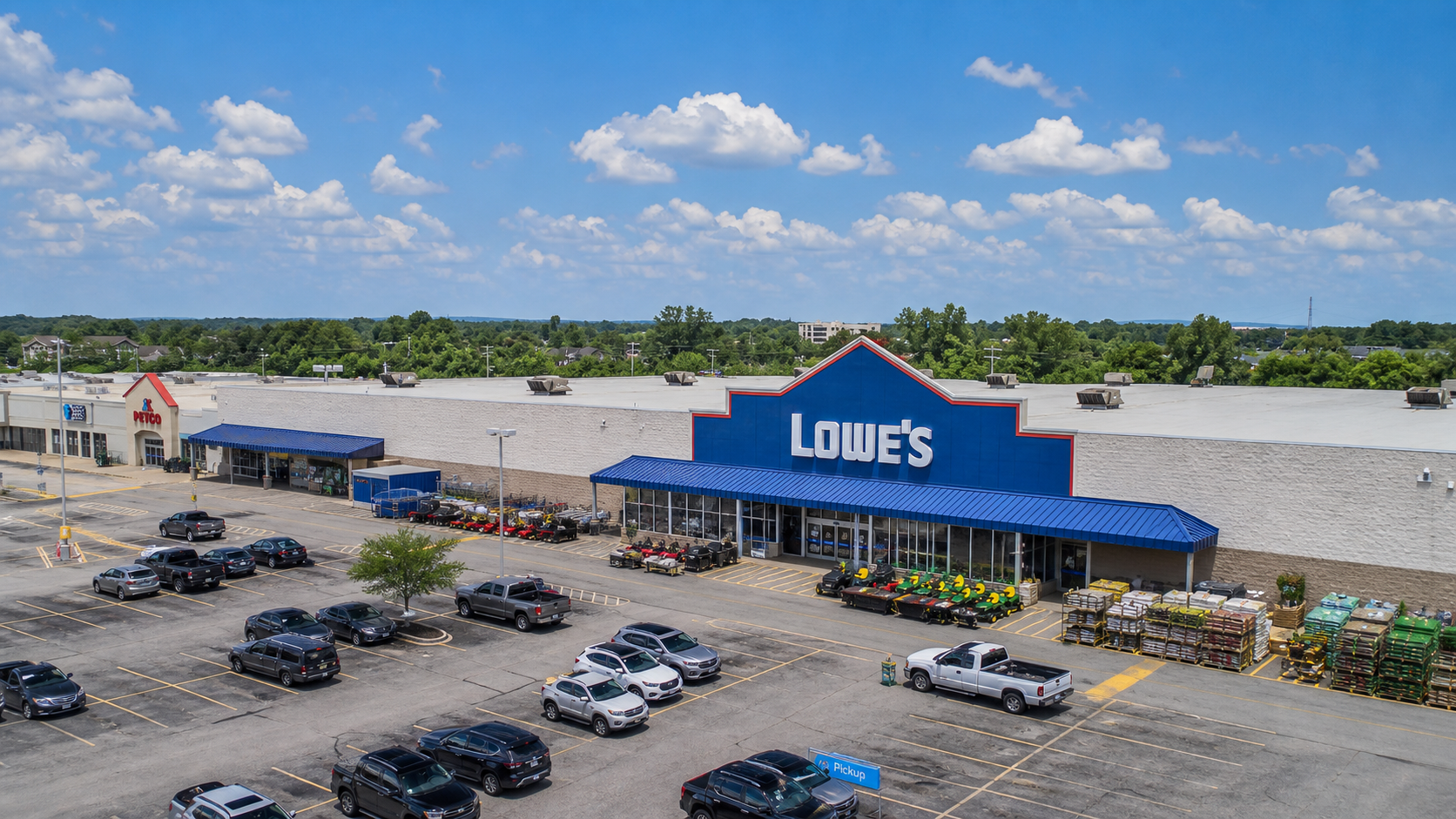 Aerial view of a busy shopping center with parking lots, storefronts, and surrounding trees
