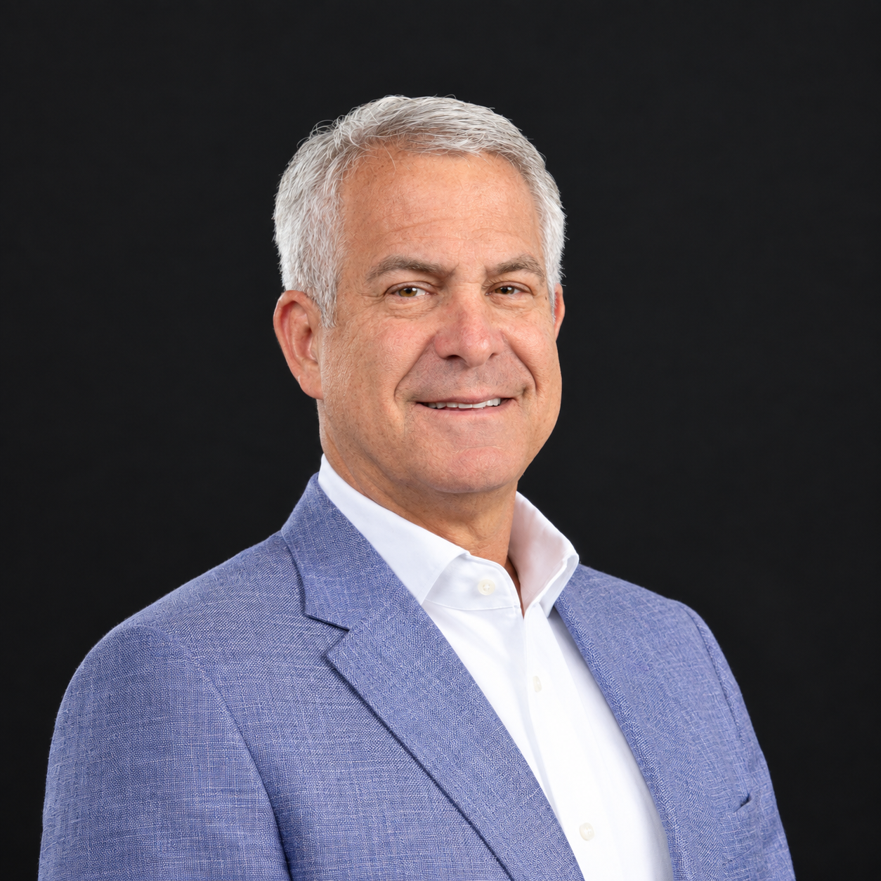 Smiling professional in a navy blazer and white shirt against a neutral backdrop