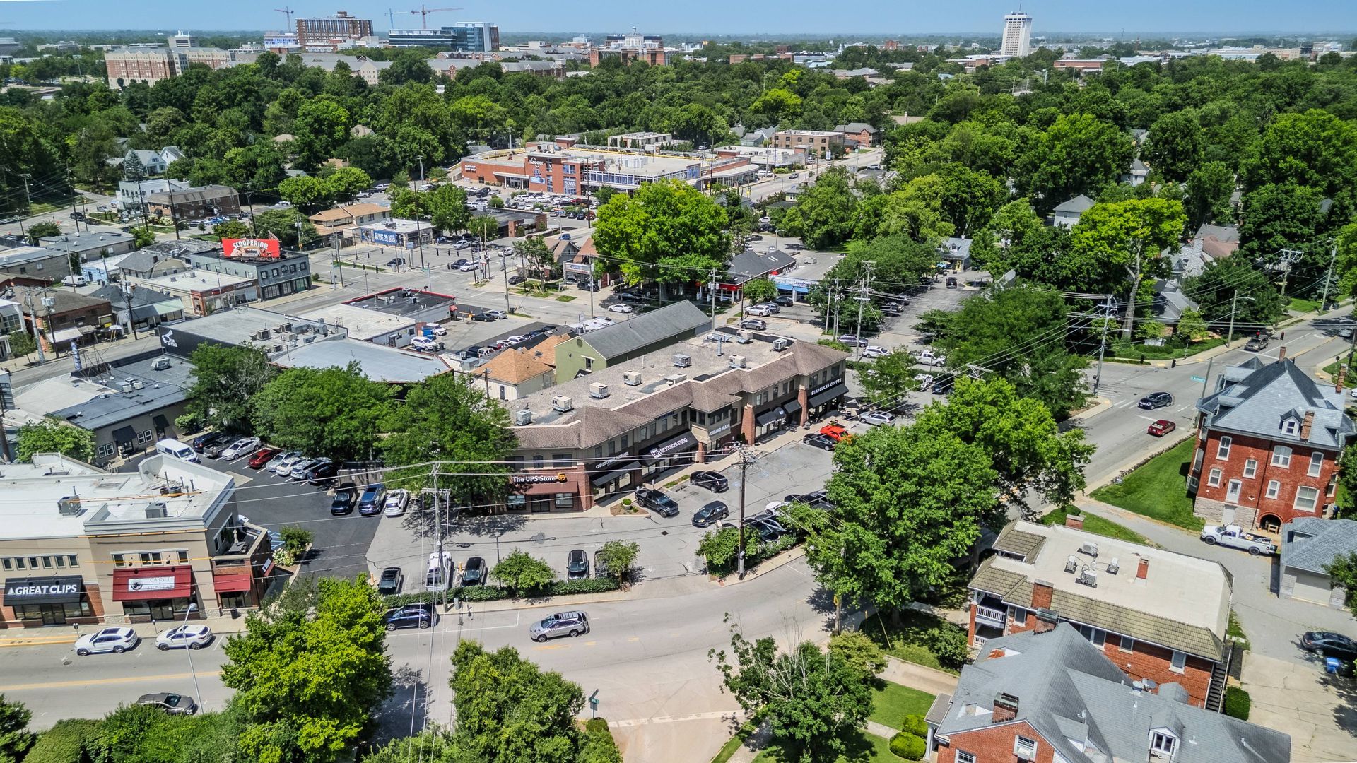 Aerial view of a leafy downtown with shops, parked cars, and streets on a sunny day