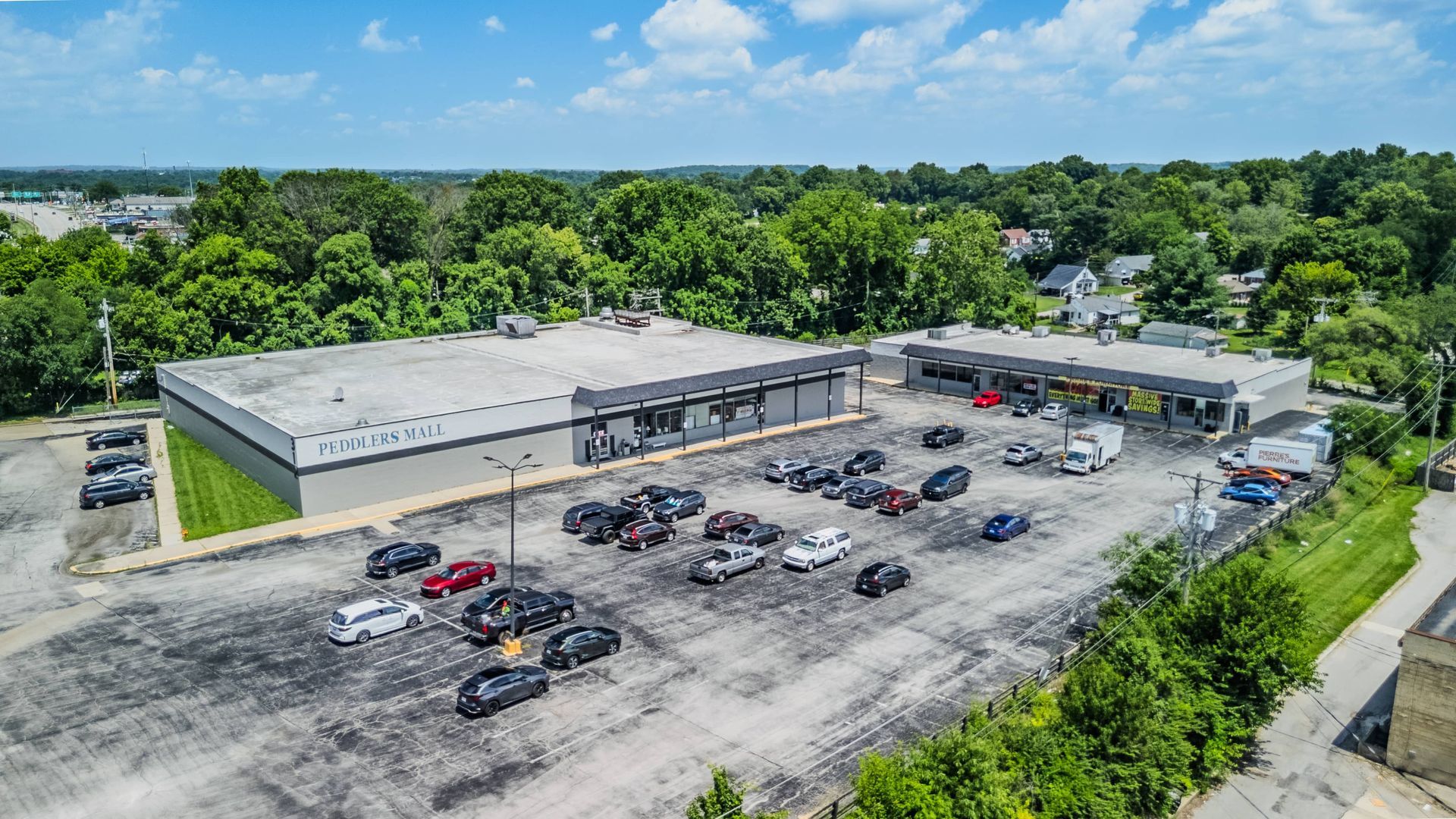 Cars waiting at a green-roof gas station with bushes and a grassy median in front