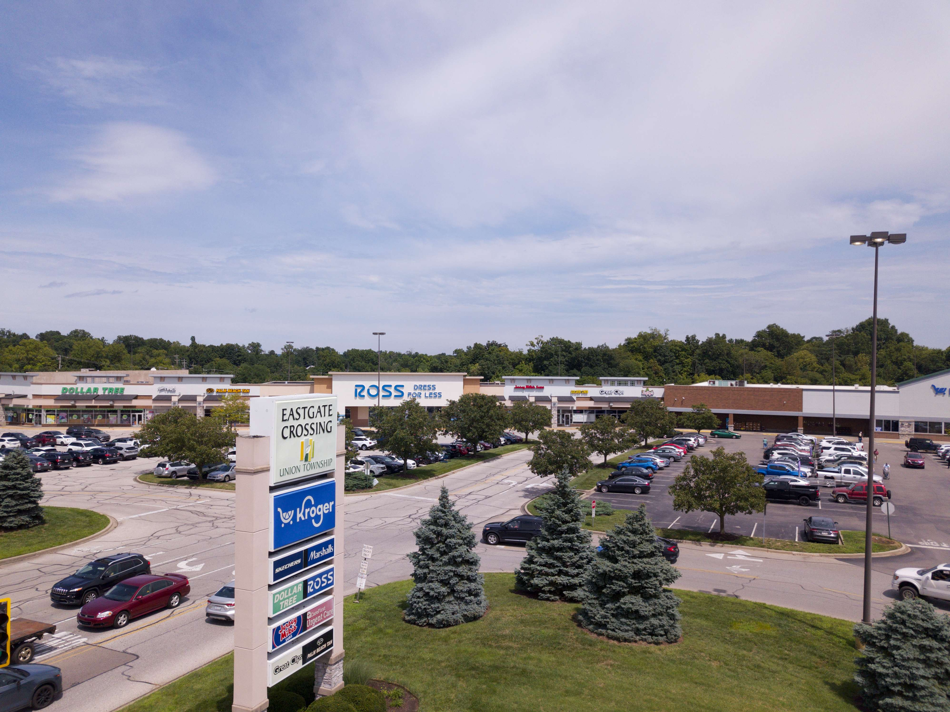Gas station with green canopy, several cars at the pumps, and a grassy foreground.