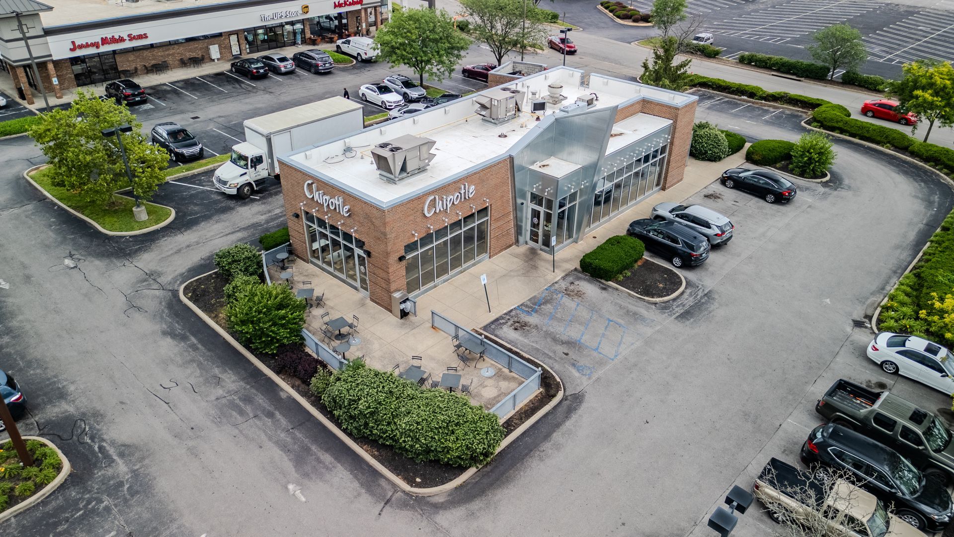 Aerial view of a brick-and-glass restaurant with a drive-thru and parking lot.