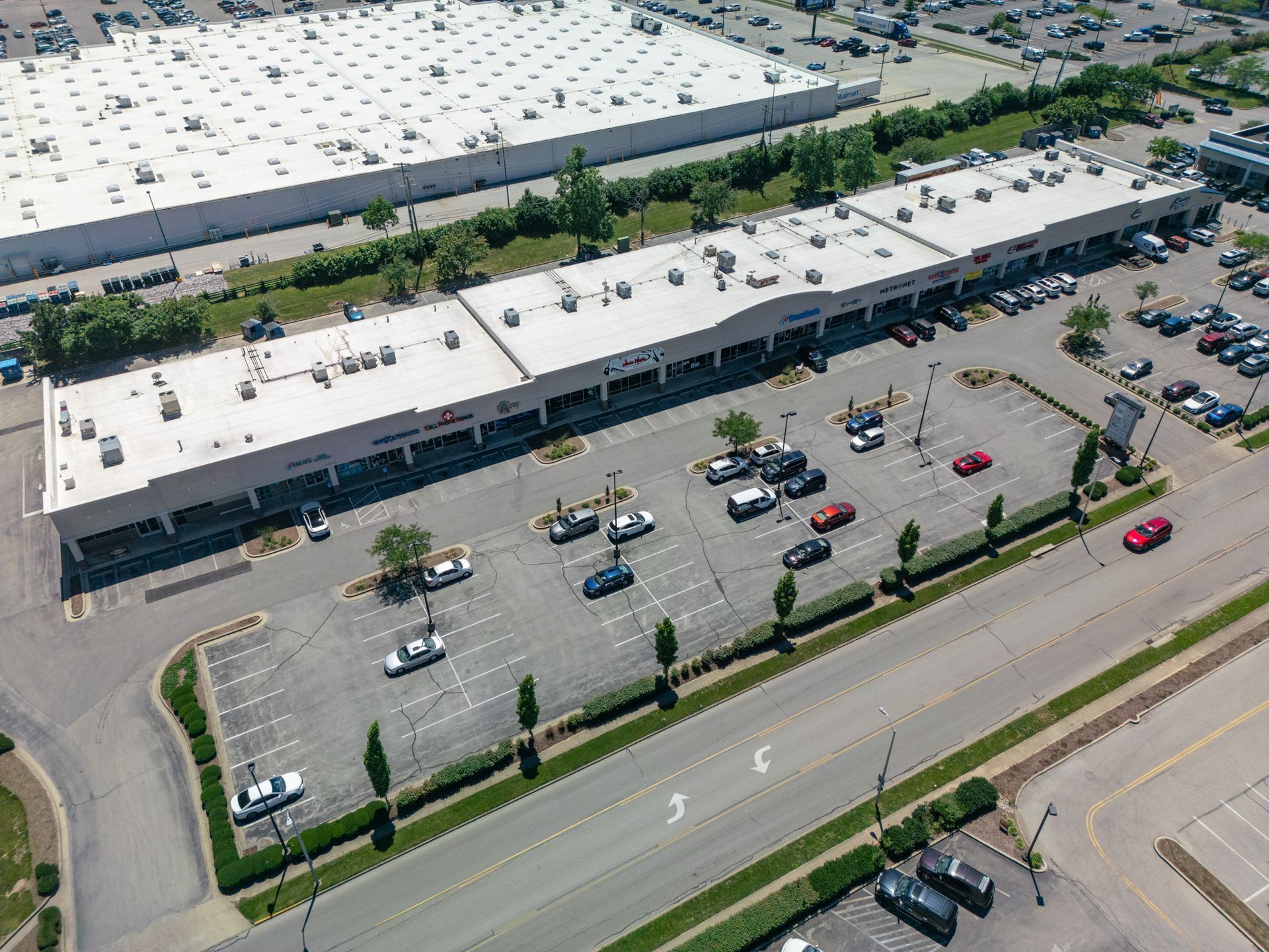 Cars waiting at a green-roof gas station with bushes and a grassy median in front