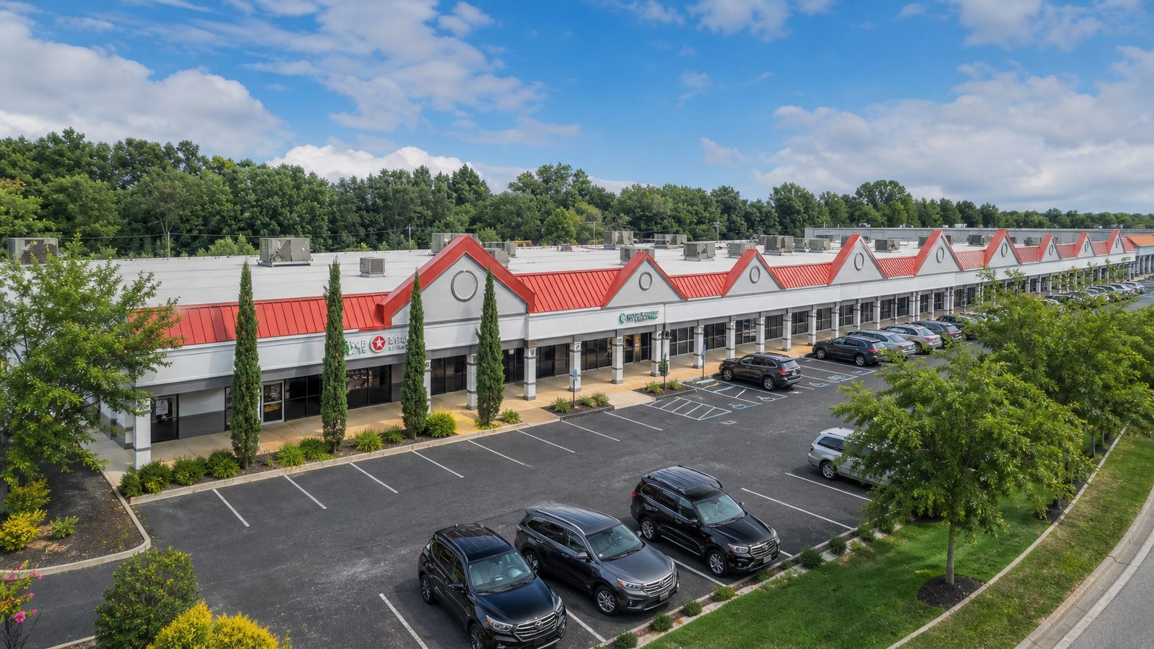 Aerial view of a brick-and-glass restaurant with a drive-thru and parking lot.