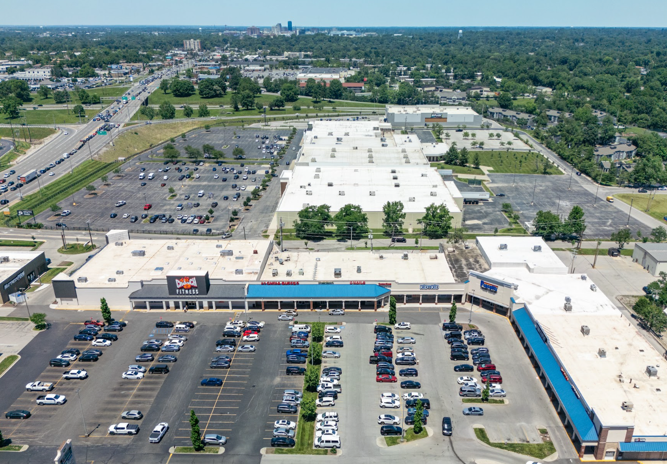 Aerial view of a large shopping center with a busy parking lot and surrounding roads.