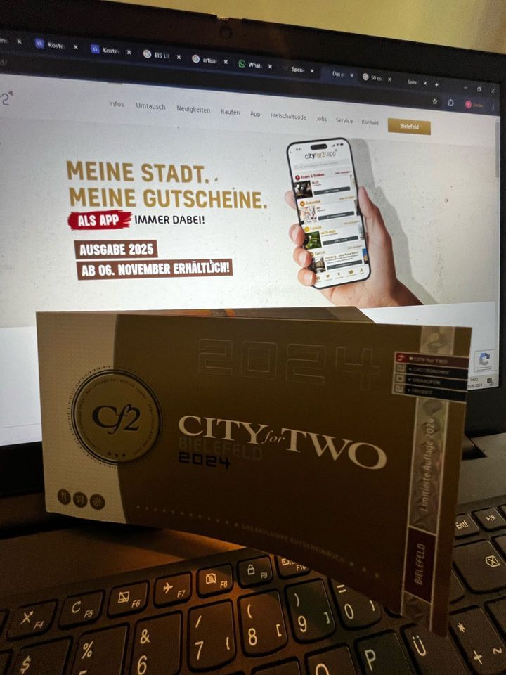 City for two Bucg mit City for two App im Hintergrund auf dem Monitor.