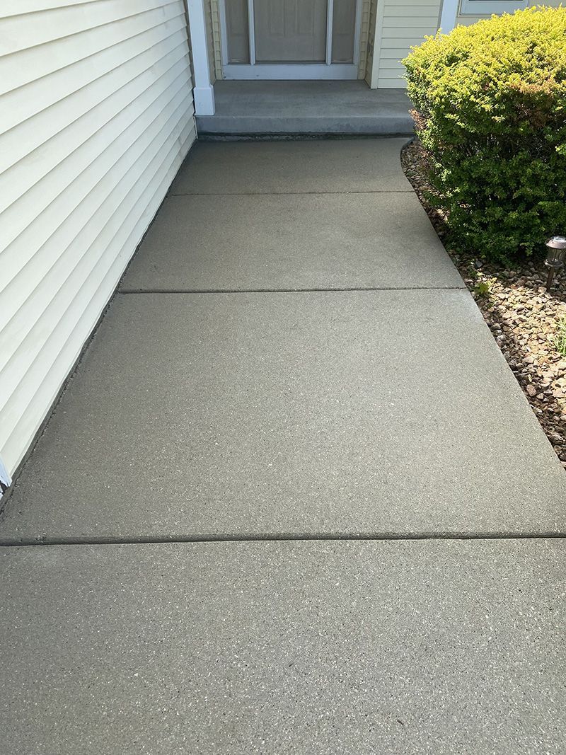 a clean concrete walkway leading to the front door of a house