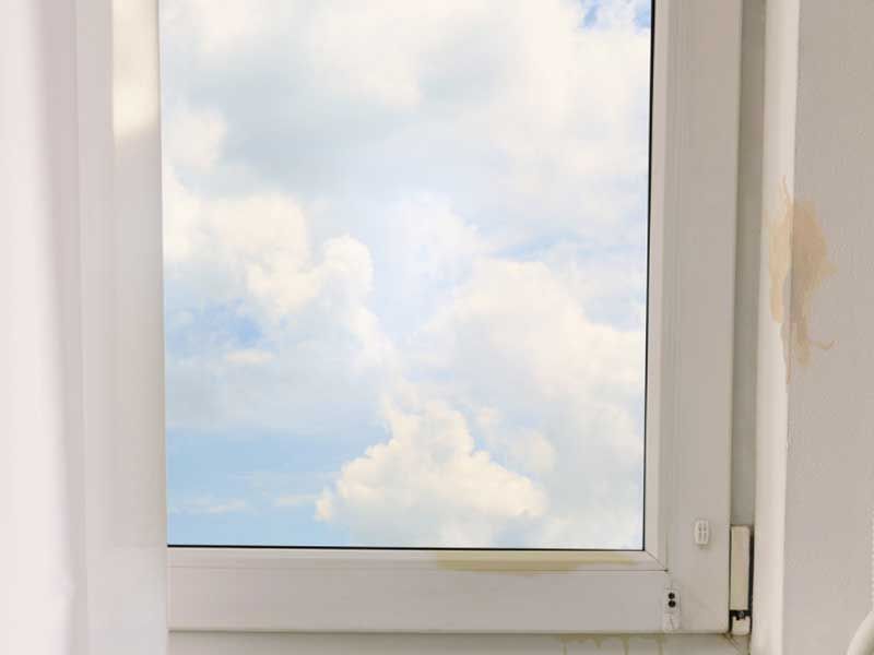 a window with a view of a cloudy sky through it .