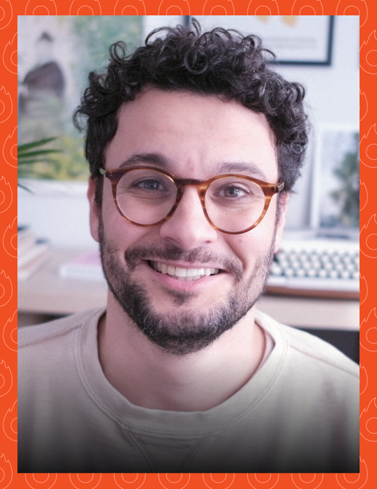 Um homem de óculos e barba sorri para a câmera