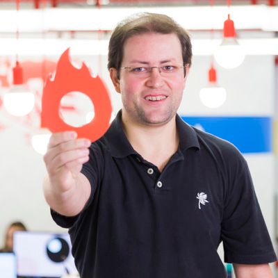 Um homem de camisa preta está segurando uma chama vermelha