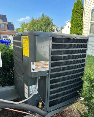 Outdoor gray HVAC unit beside a house, with vents and warning labels in a residential yard