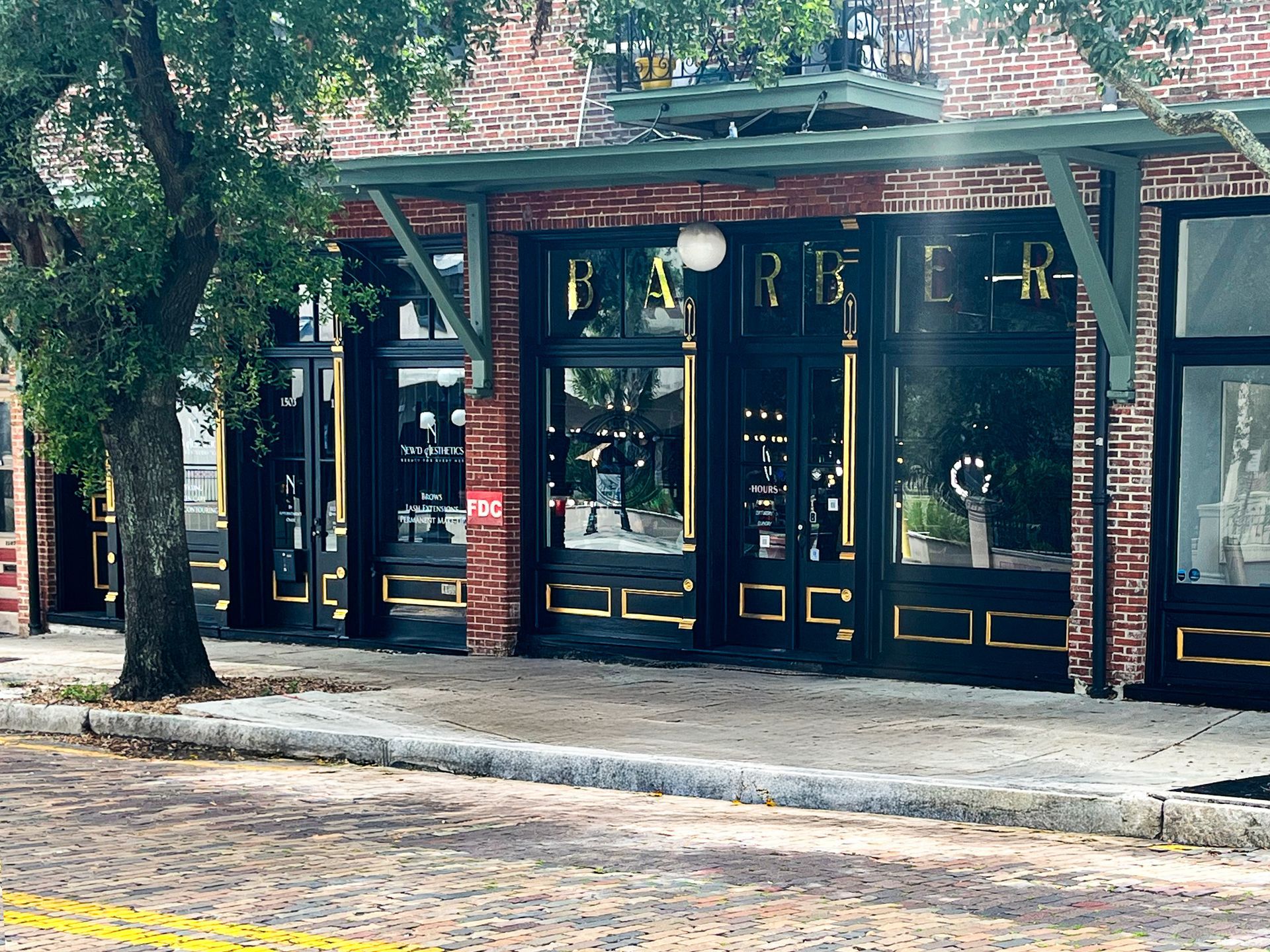A brick storefront with large black-framed windows and a gold 