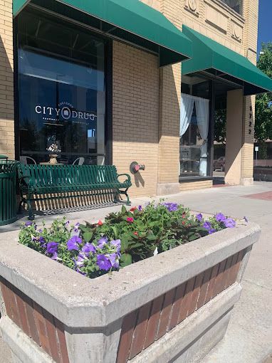A planter with purple flowers in front of a building with a green awning.