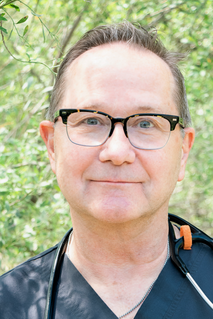 A man wearing glasses and a stethoscope is smiling for the camera.