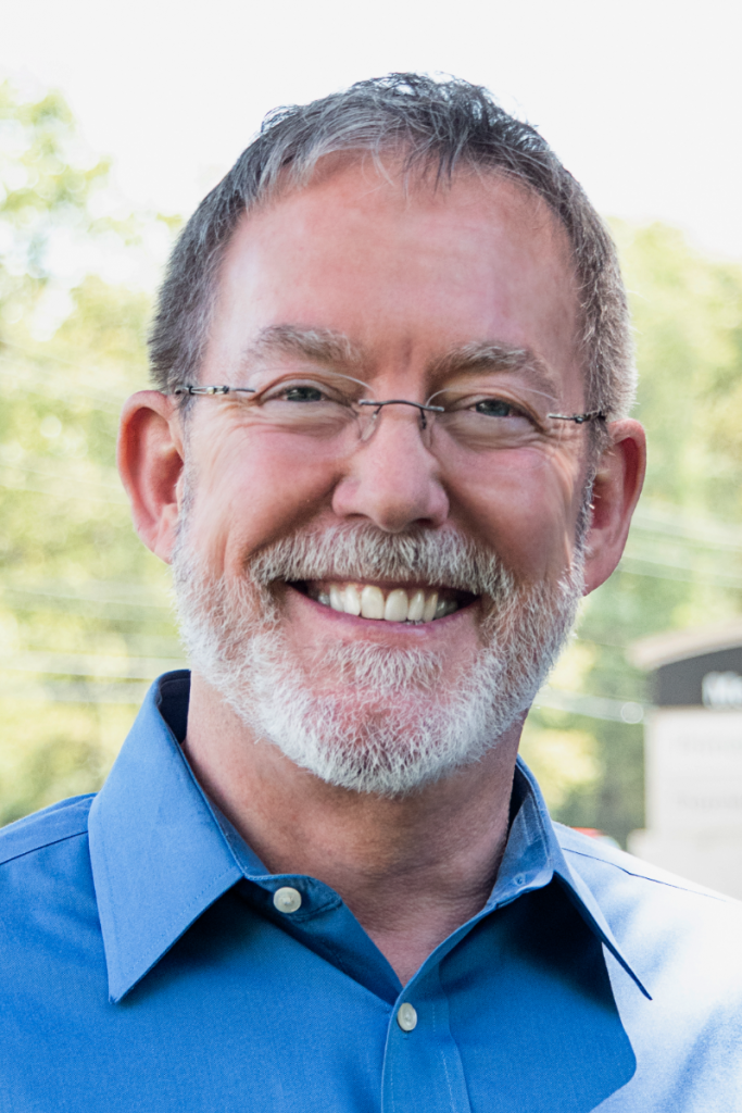 A man with glasses and a beard is smiling for the camera.