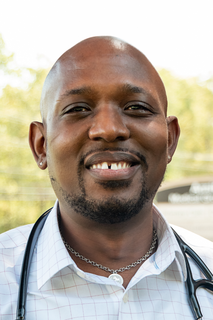 A man with a stethoscope around his neck is smiling for the camera.