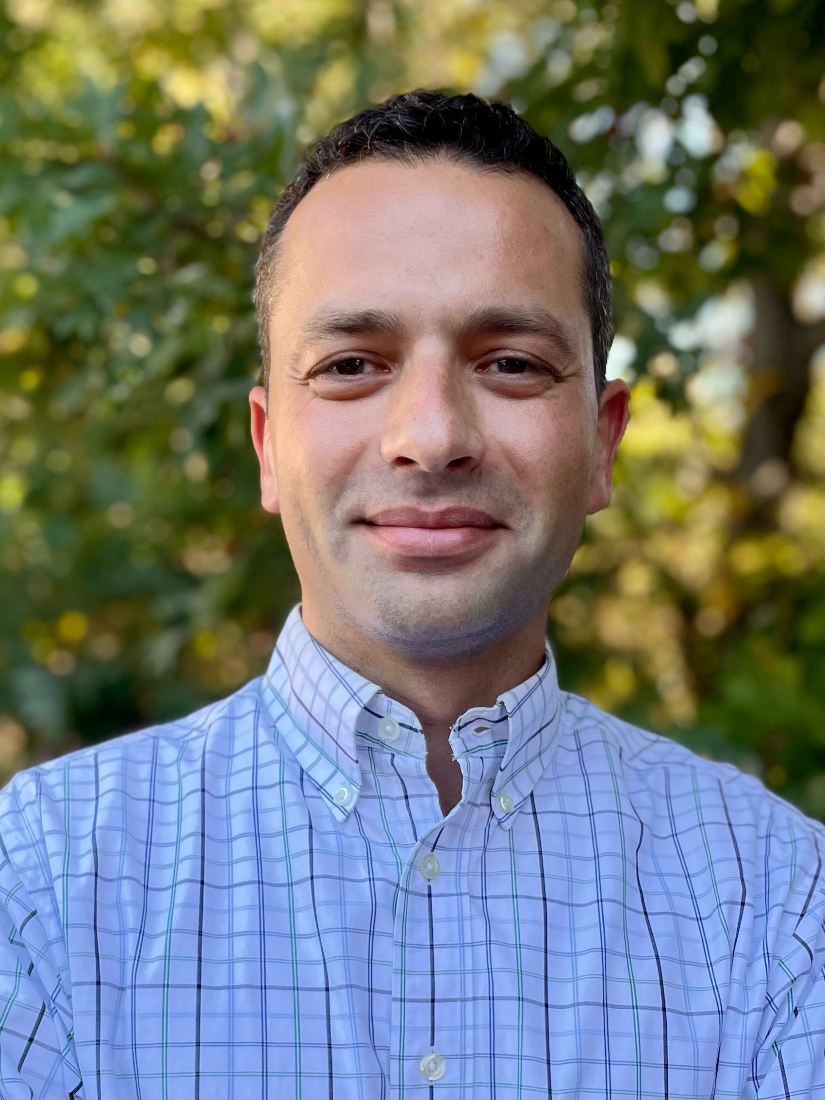 A man in a plaid shirt is smiling for the camera.
