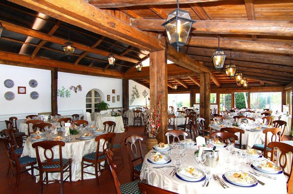 Interno del ristorante con travi in legno, tavoli apparecchiati per i commensali.