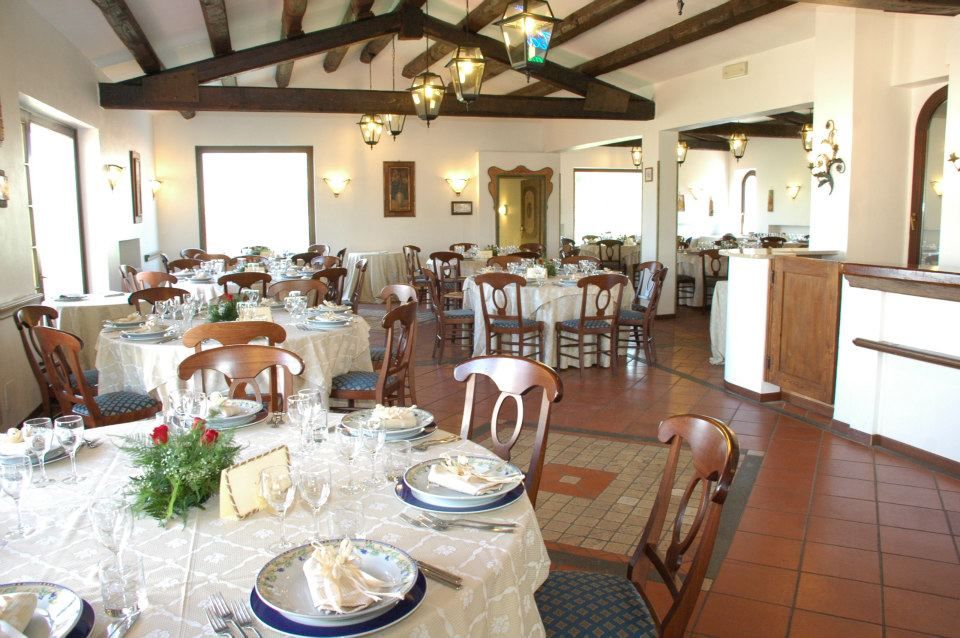 Sala da pranzo del ristorante con tavoli apparecchiati per gli ospiti, travi in legno e pavimento piastrellato.