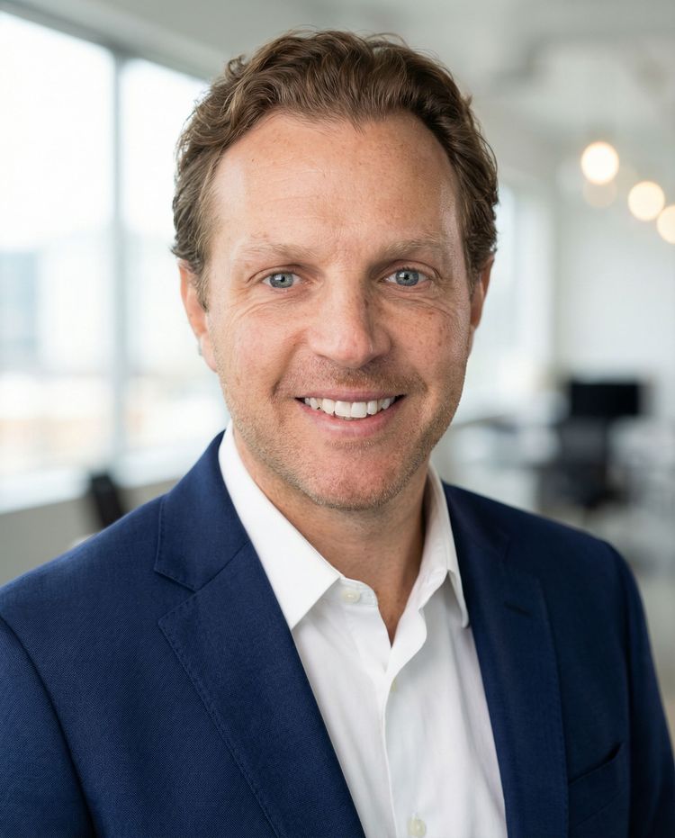 Smiling man in a navy blazer and white shirt in a bright office setting