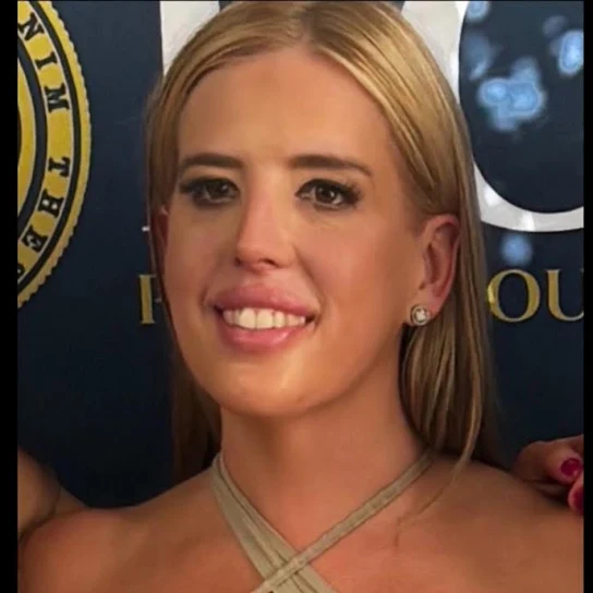 Smiling blonde woman in a beige halter top at an event backdrop