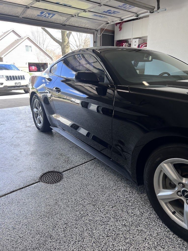 A black mustang is parked in a garage.