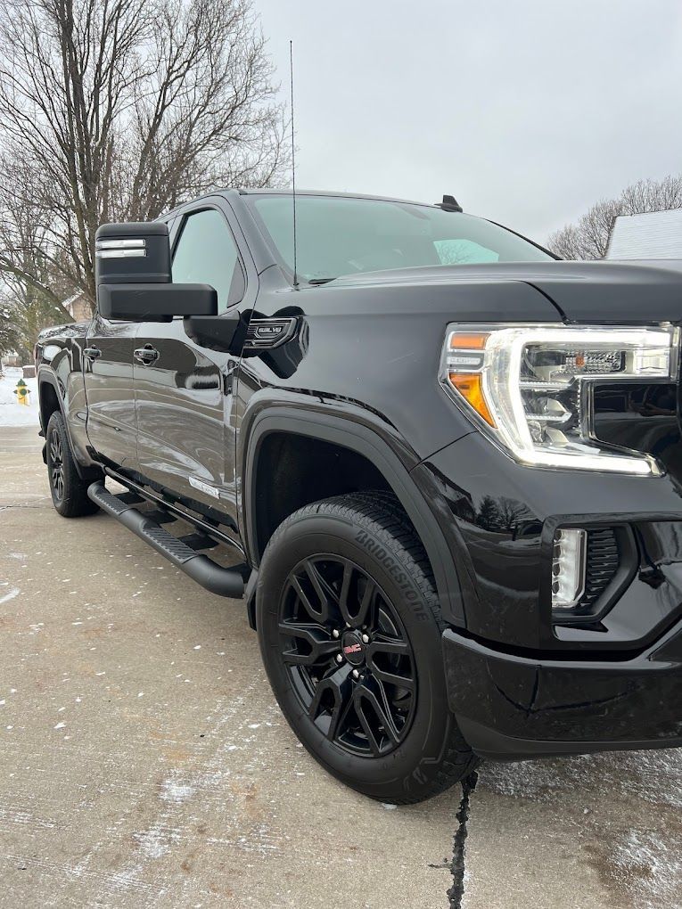 A black truck is parked on the side of the road in the snow.