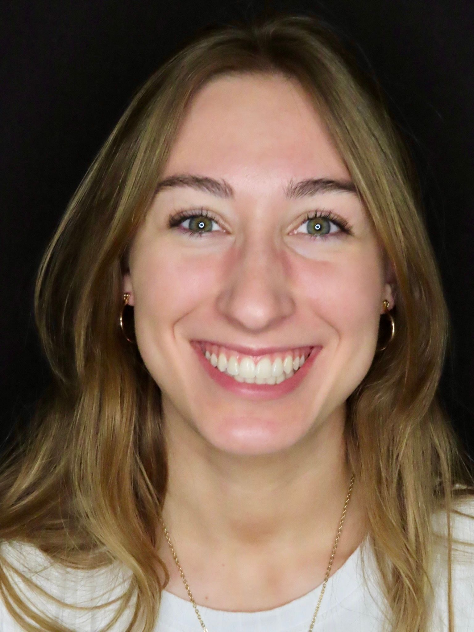 Smiling woman with shoulder-length hair against a dark background