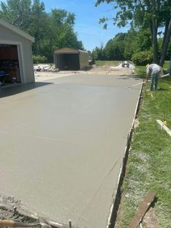 A man is working on a concrete driveway in front of a garage.