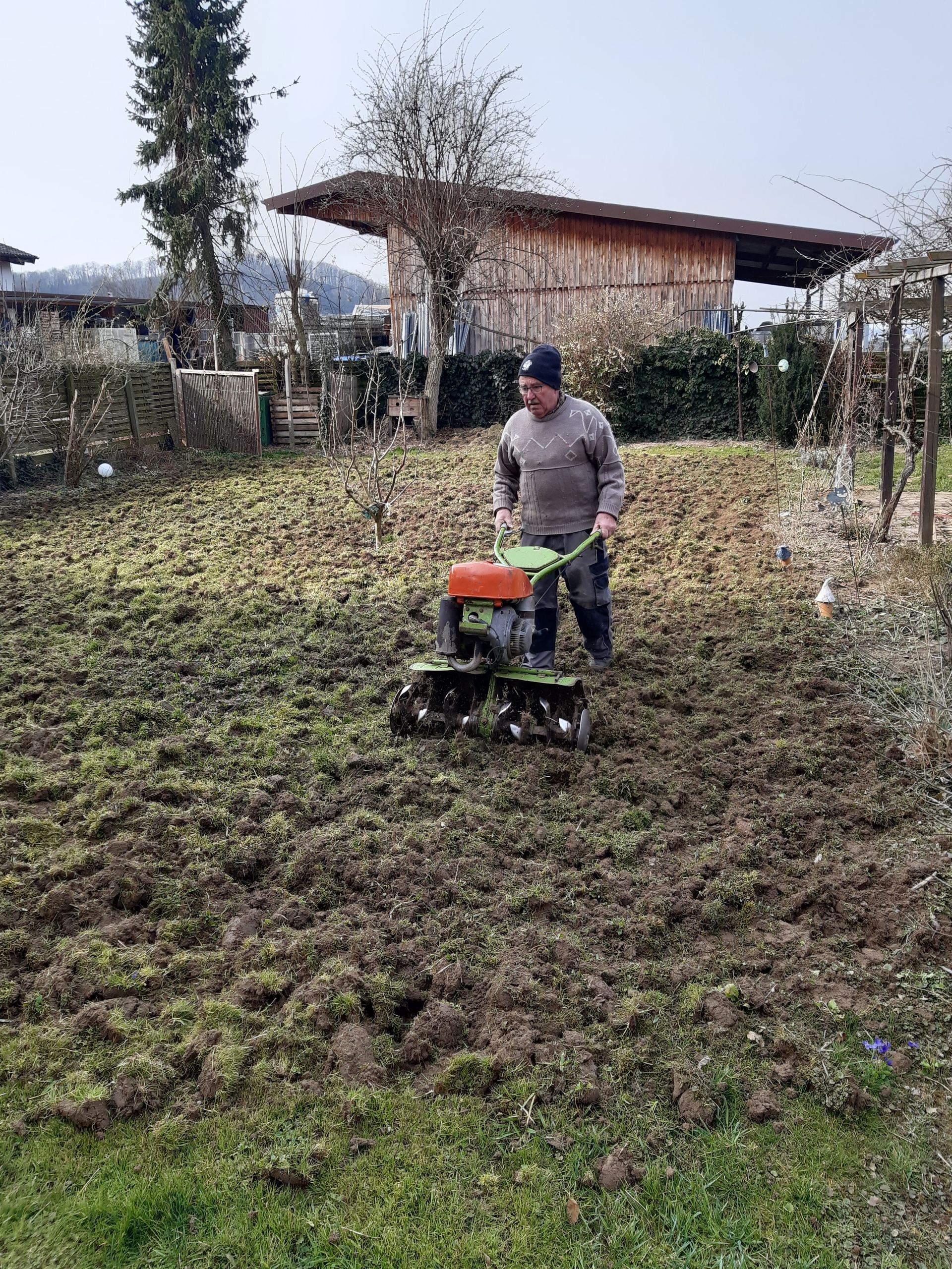 Ein Mann pflügt mit einem kleinen Traktor ein Feld.
