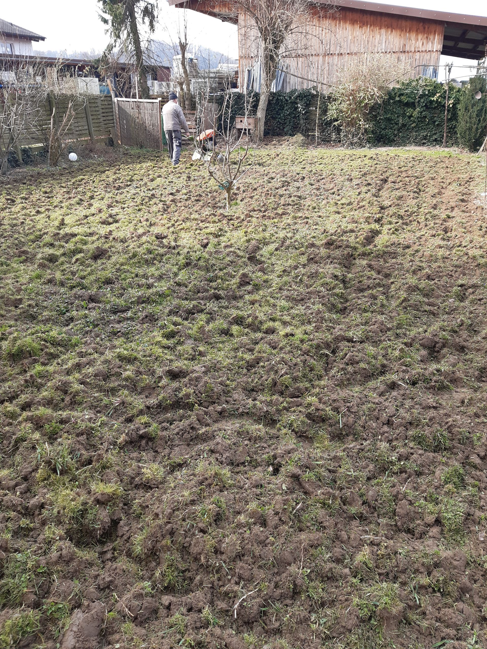 Ein großes Feld aus Gras und Erde mit einem Haus im Hintergrund.