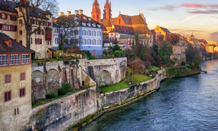 blick auf die farbenfrohen häuser der innenstadt von basel vom flussufer aus bei sonnenuntergang