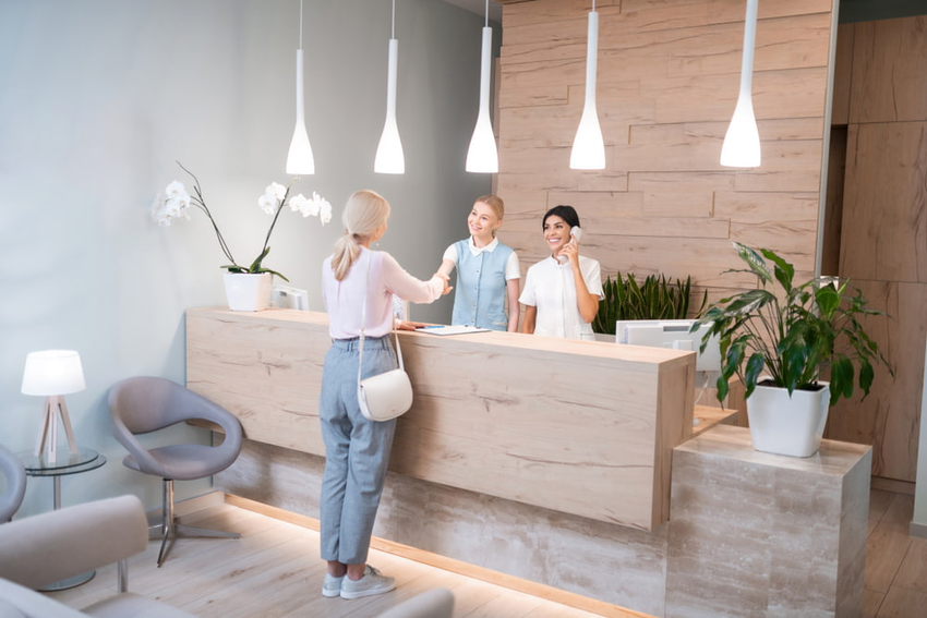 A woman is standing at a reception desk in a dental office.