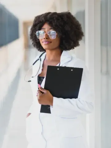A woman in a lab coat is holding a clipboard and a stethoscope.