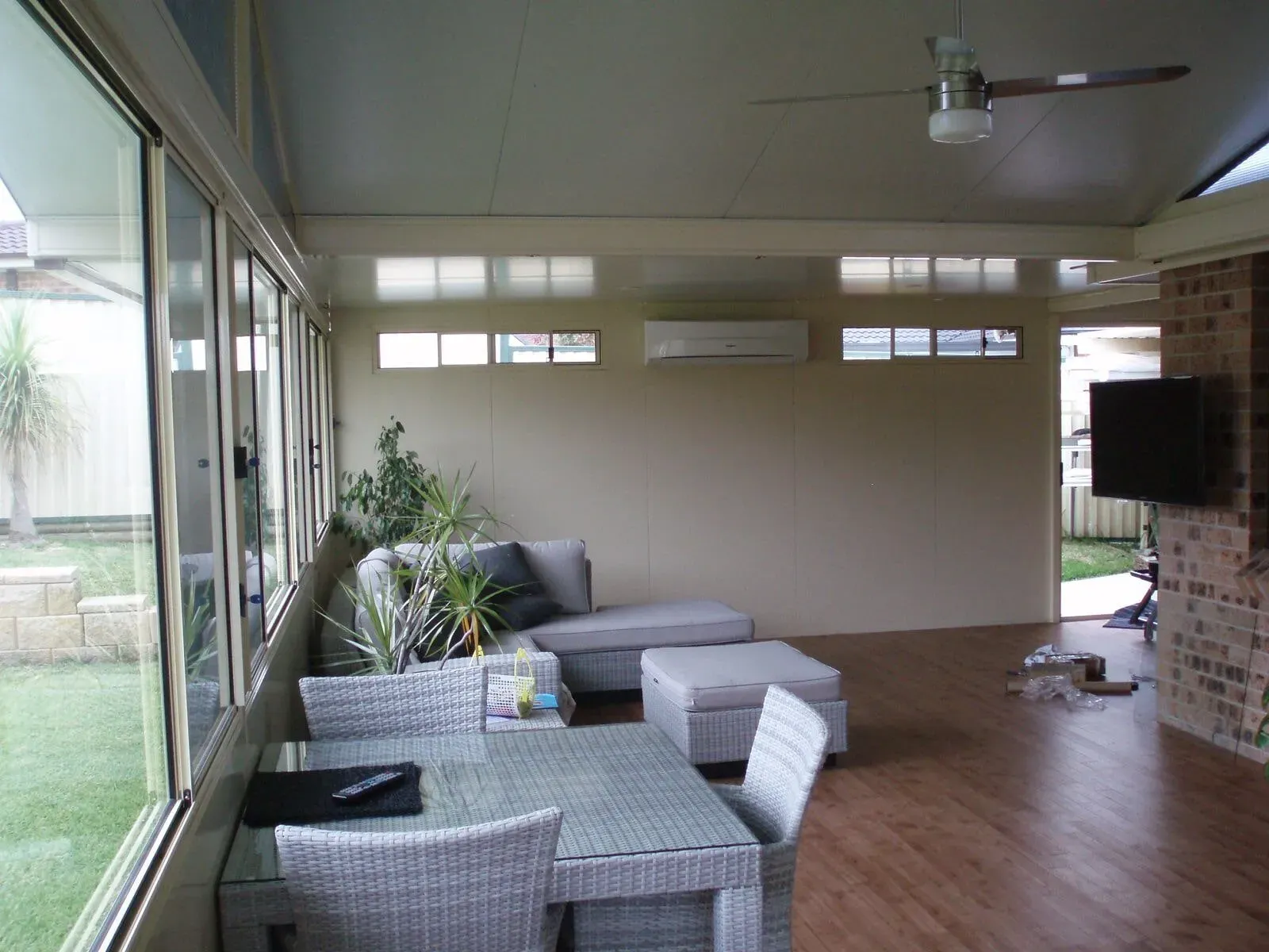A sunroom with a table and chairs and a ceiling fan — Hunter & Mid Coast Patios In Hamilton, NSW