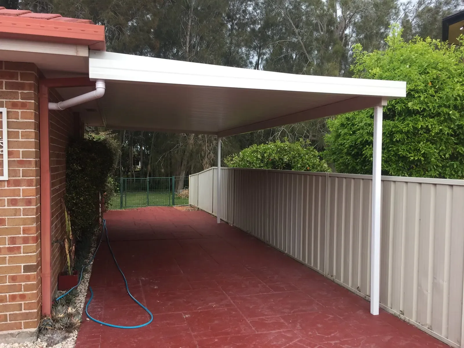 A white carport is attached to a brick house — Hunter & Mid Coast Patios In Lake Macquarie, NSW